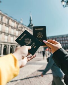 Travelers holding US passports at Plaza Mayor, Madrid, highlighting tourism and exploration.